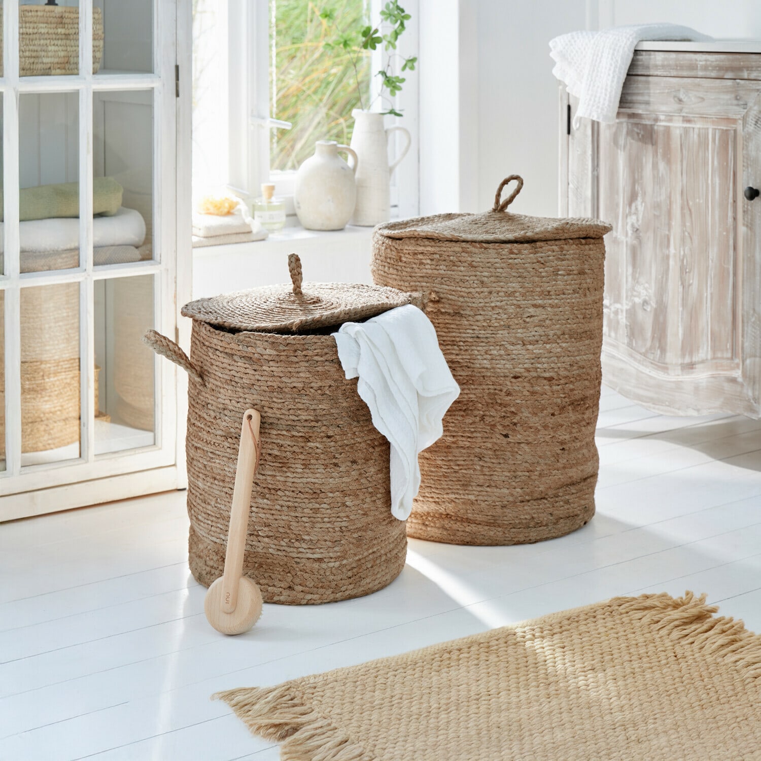 Wasmand set van 2 Kory Twee ronde wasmanden van natuurlijke jute in beige kleur in een lichte badkamer