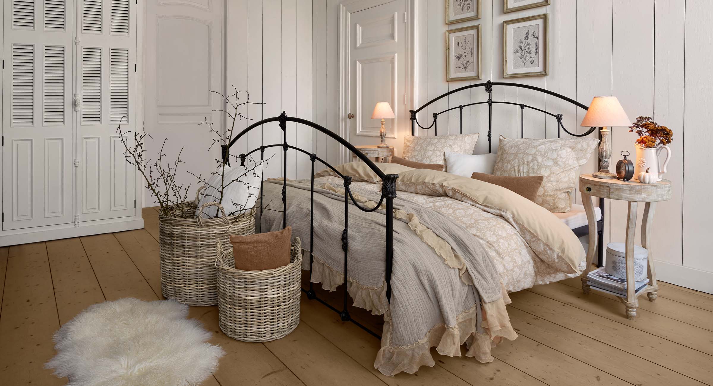 Chambre chaleureuse avec lit en métal noir et literie crème à motif floral pour décoration cosy