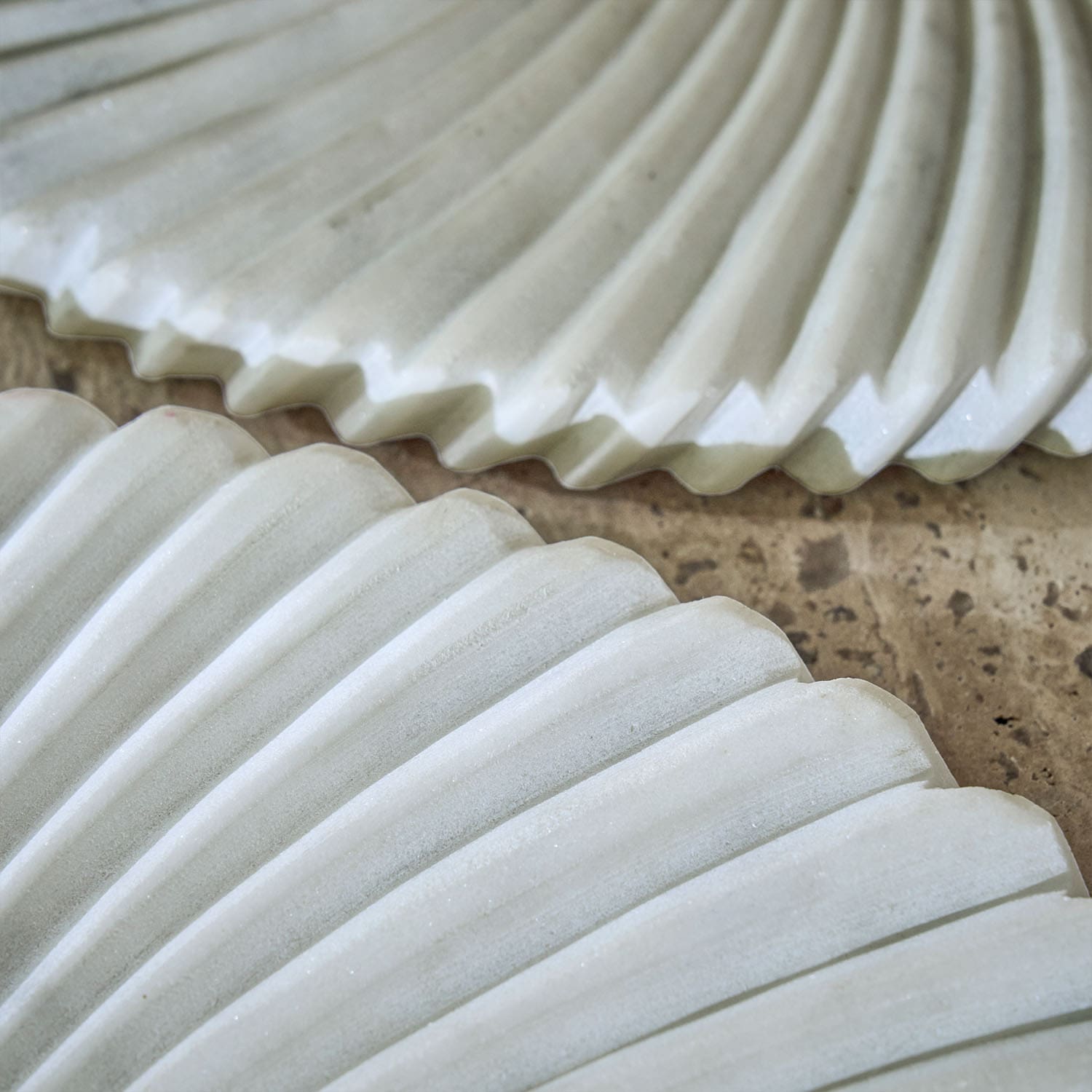 Assiettes décoratives blanches en céramique avec motif rainuré posées sur un plan de travail en pierre