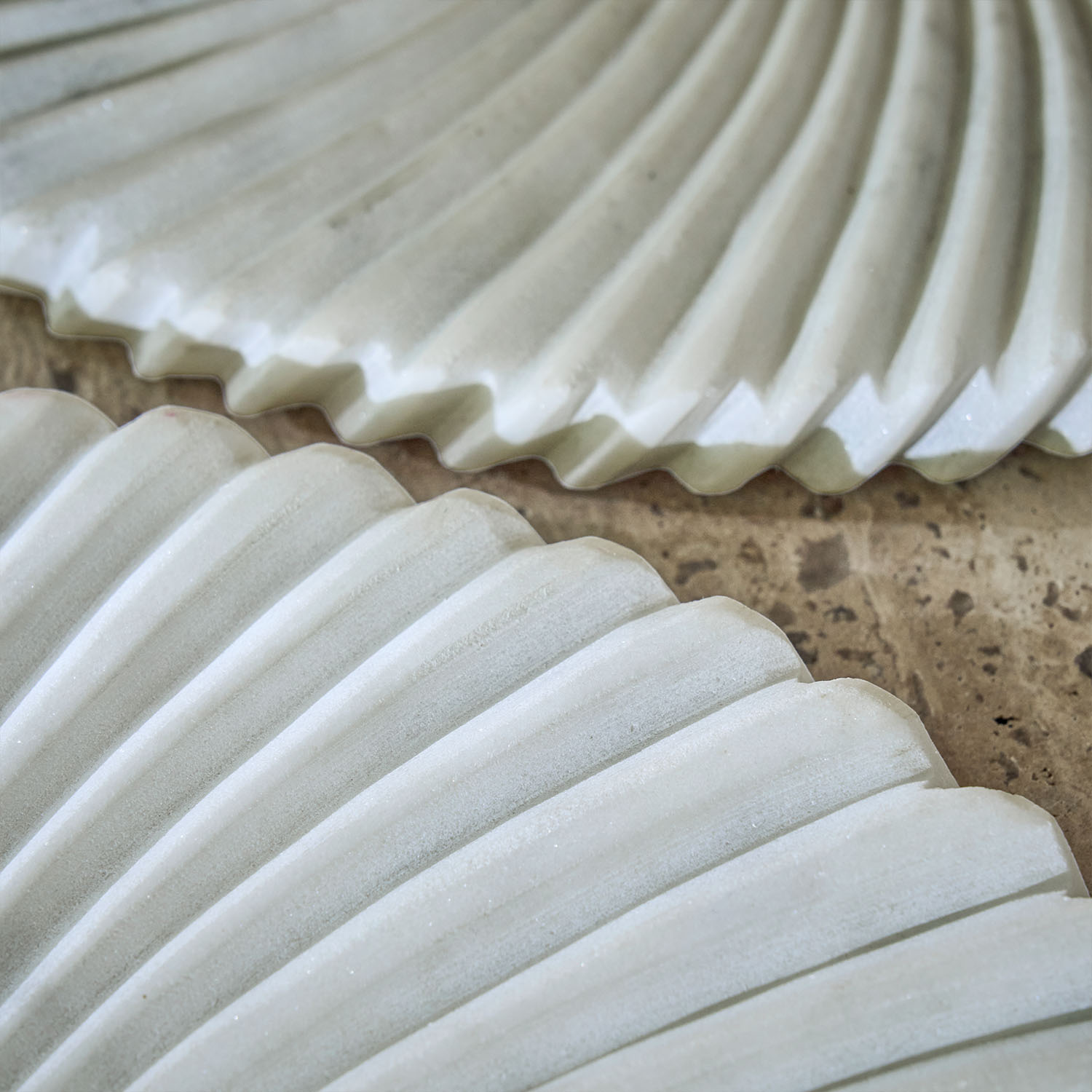 Assiettes décoratives blanches en céramique avec motif rainuré posées sur un plan de travail en pierre