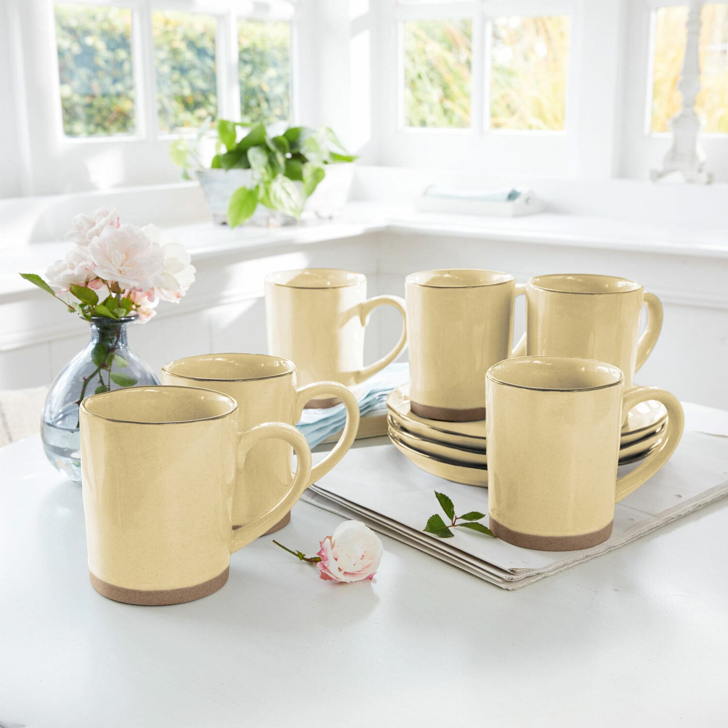 Ensemble de six mugs en céramique jaune avec base marron sur une table claire dans une cuisine lumineuse