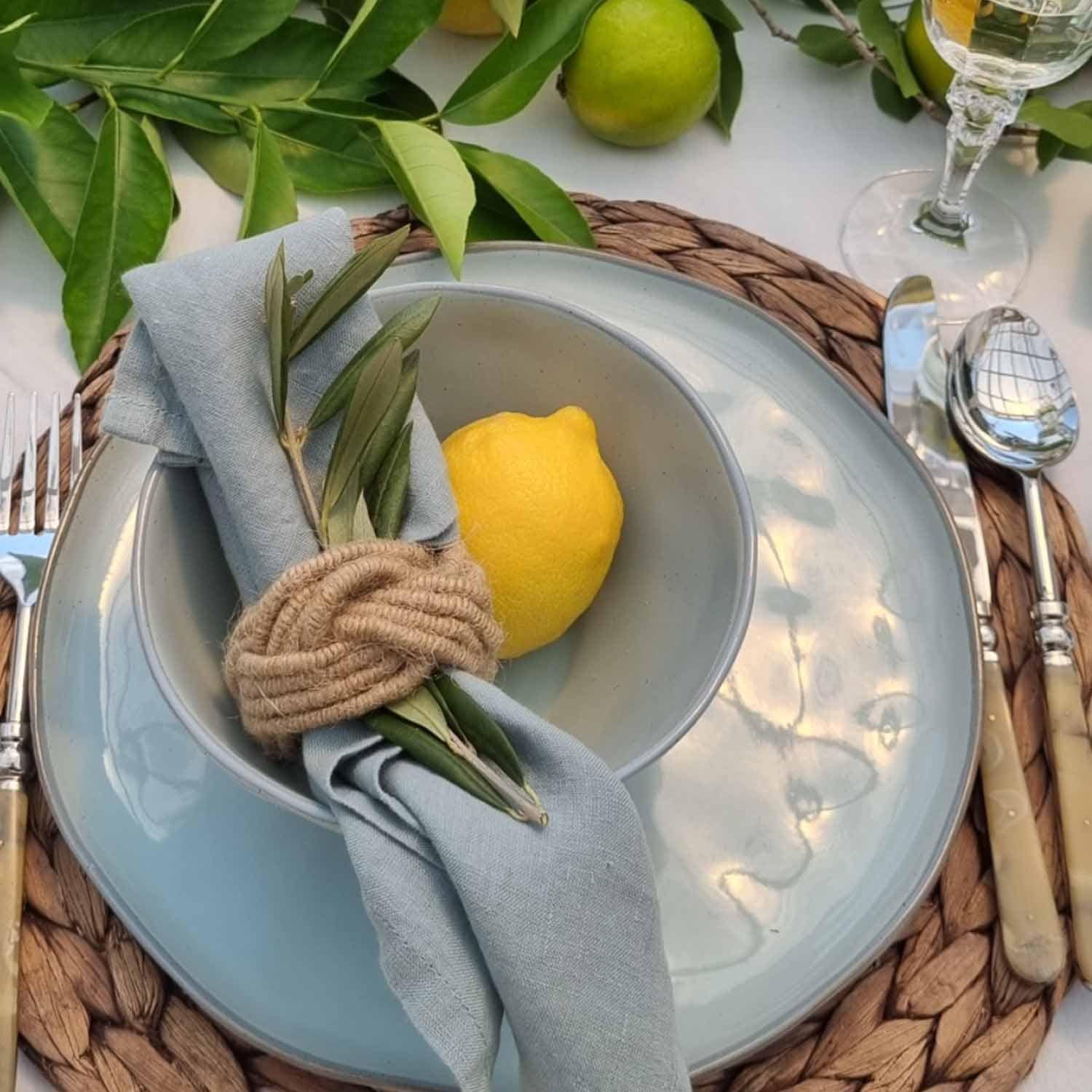 Blauw keramisch servies met linnen servet en citroen op gevlochten placemat