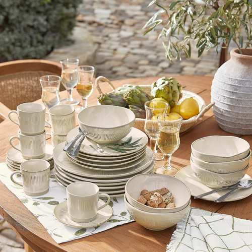 Set crème keramiek met groen bladmotief op houten tafel buiten