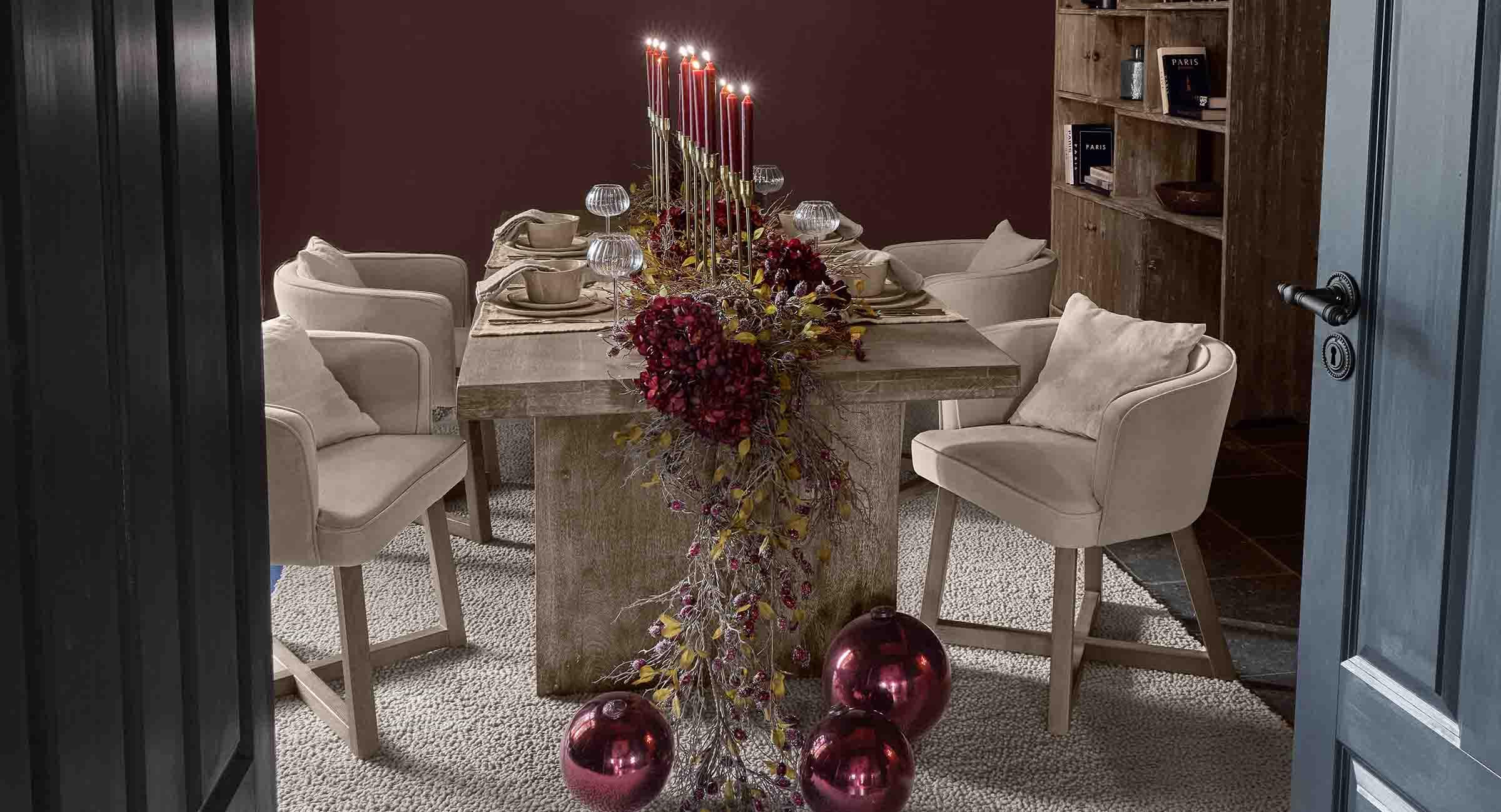 Table à manger élégante avec chaises beige et décoration festive rouge avec bougies allumées