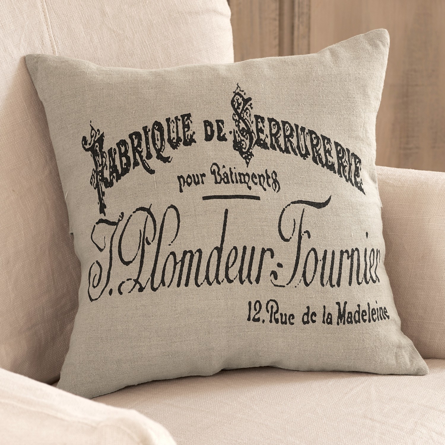 Beige linnen kussen met zwarte Franse print op lichte bank, interieurdecoratie