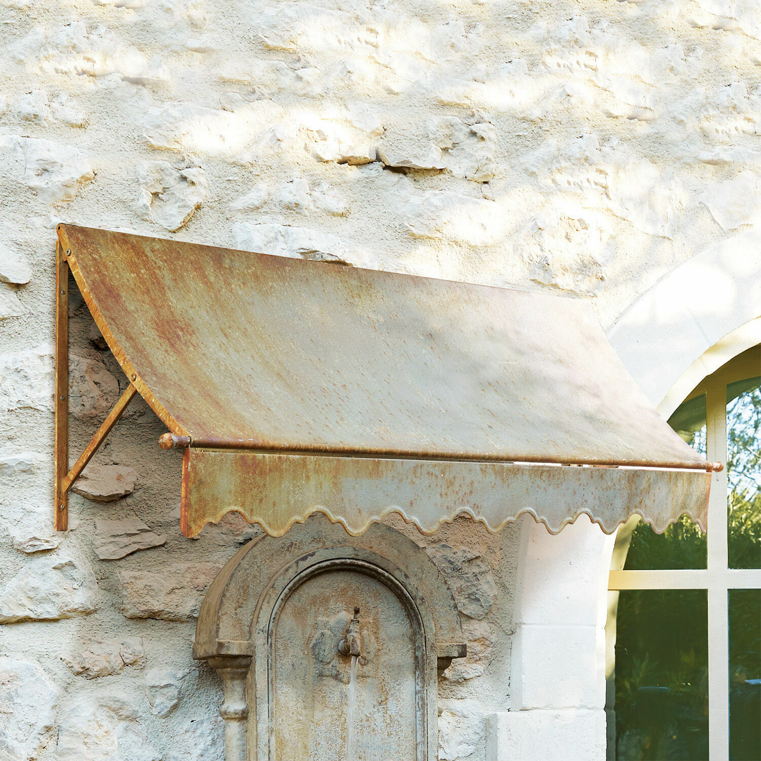 Auvent Maltot Auvent en métal rouillé fixé sur un mur en pierre avec une fenêtre et une fontaine ancienne