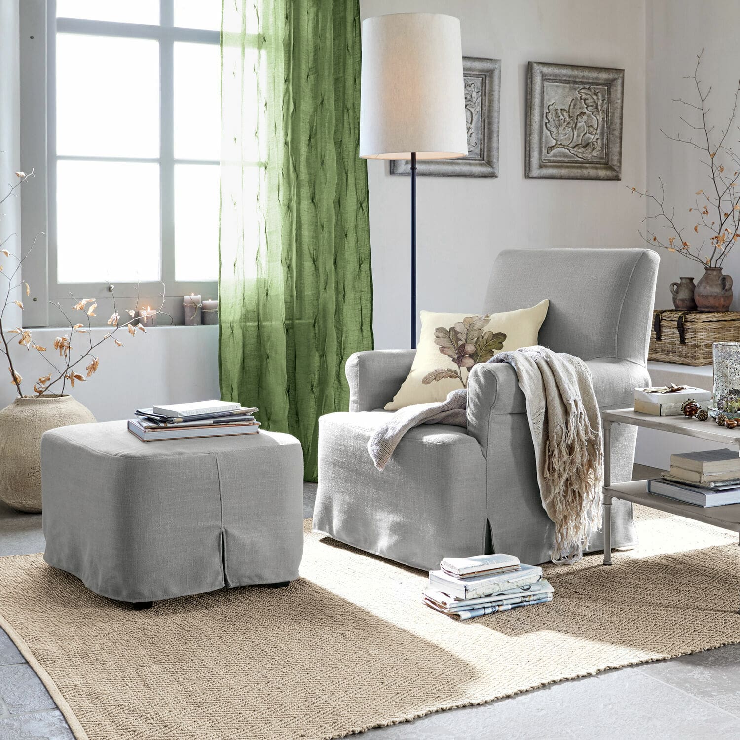 Fauteuil avec pouf Nasour Fauteuil gris avec repose-pieds assorti et rideaux verts dans un salon lumineux avec tapis en jute