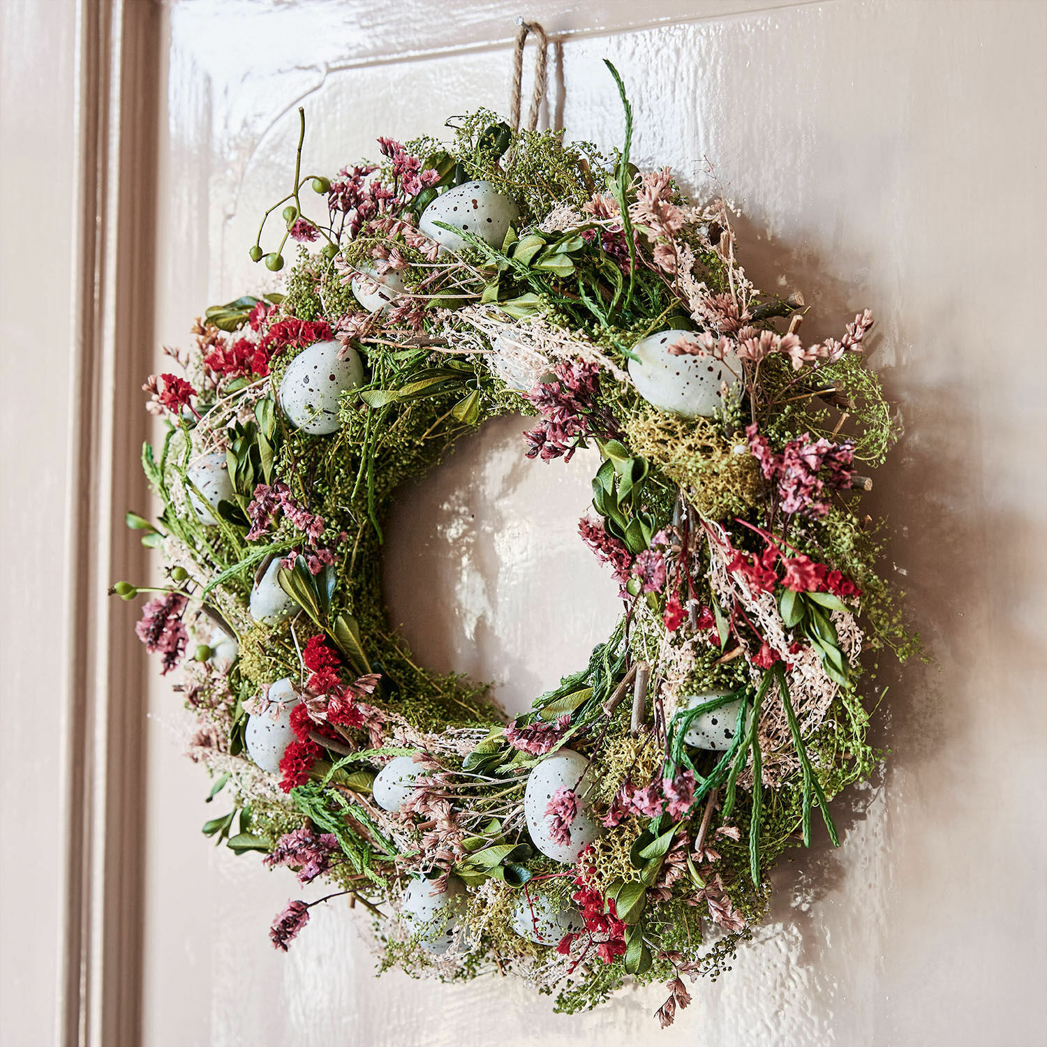 Krans Kolton Decoratieve krans van groene bladeren, rode bloemen en blauwe eieren als lentebehang aan de deur