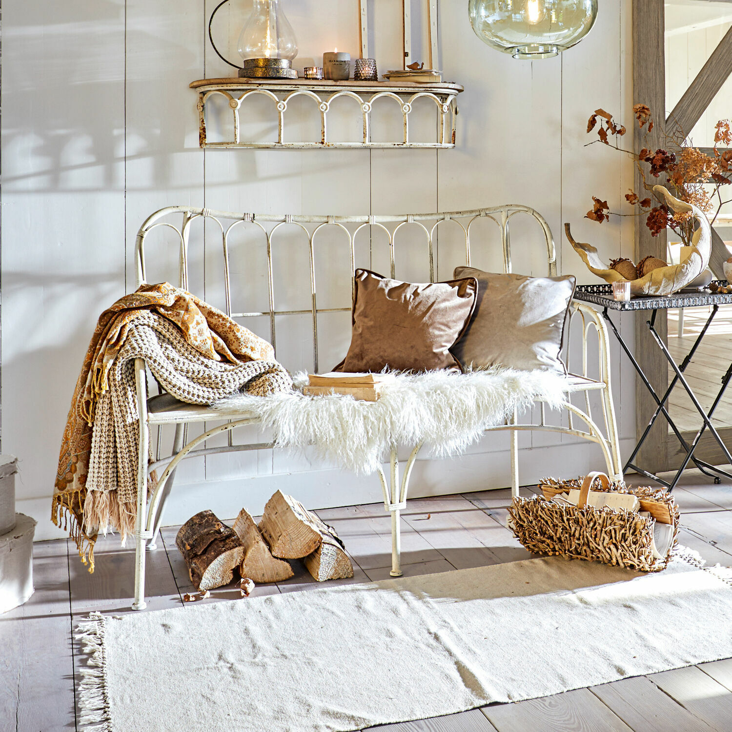 Banc Beauclair Banc en métal blanc avec coussins doux et plaid dans un salon chaleureux au sol en bois