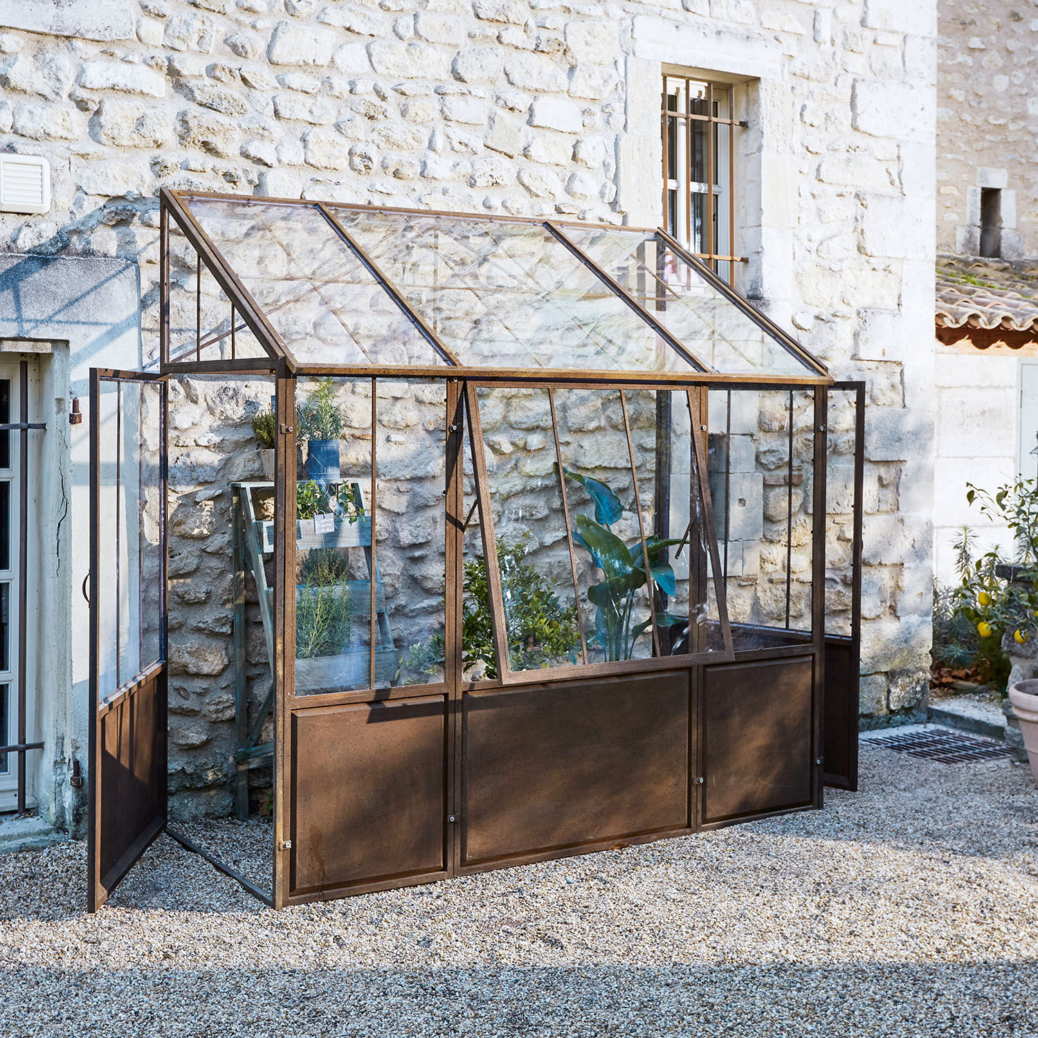 Tuinserre met roestig metalen frame en glazen panelen, ideaal voor het kweken van planten en kruiden buiten