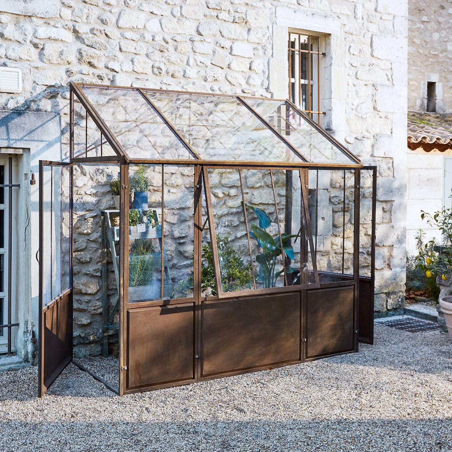 Plantenkas Essone Tuinserre met roestig metalen frame en glazen panelen, ideaal voor het kweken van planten en kruiden buiten