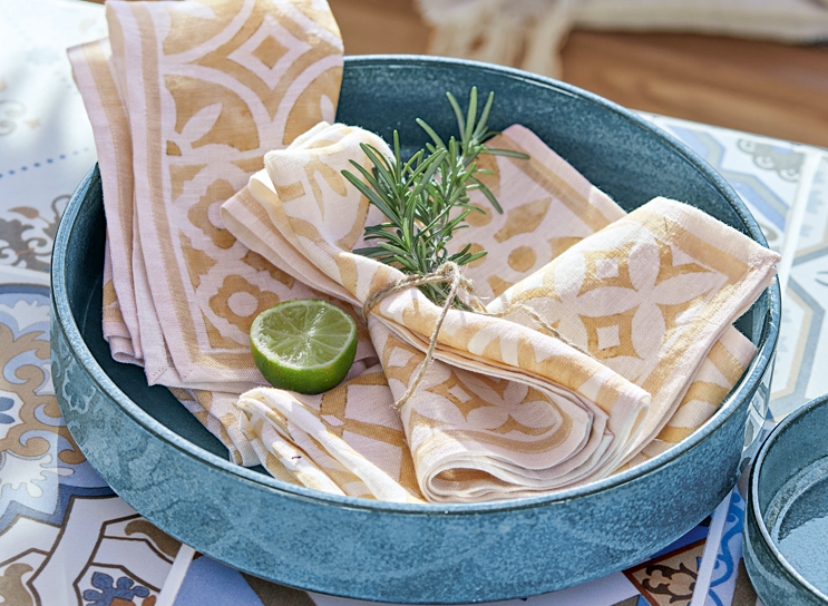 Blauwe keramische schaal met beige-witte linnen servetten en limoenpartje, mediterrane stijl