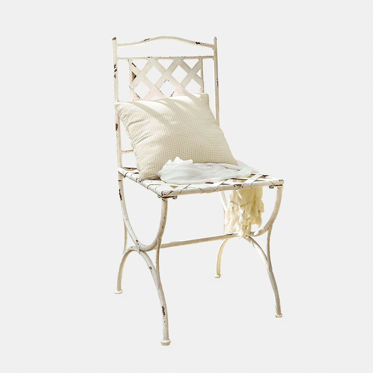 Vintage metalen stoel in wit met geruit kussen en lichte sjaal erop