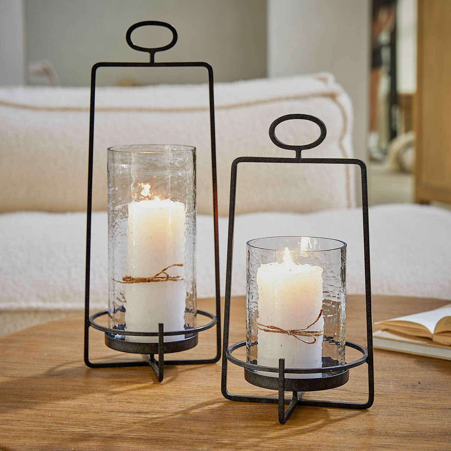 Lantaarn set van 2 Zevara Twee metalen lantaarns met helder glas en witte kaarsen op houten tafel in woonkamer