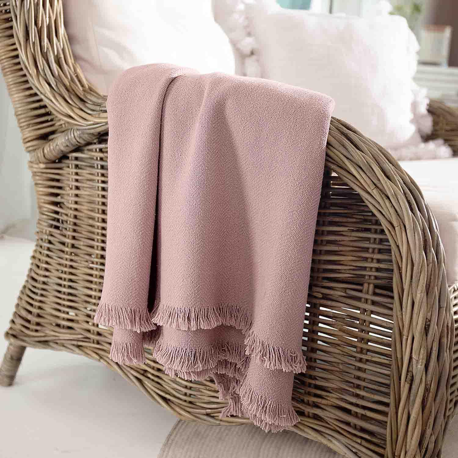 Roze zachte deken met franjes op rotan stoel, sfeervolle woondecoratie en comfort