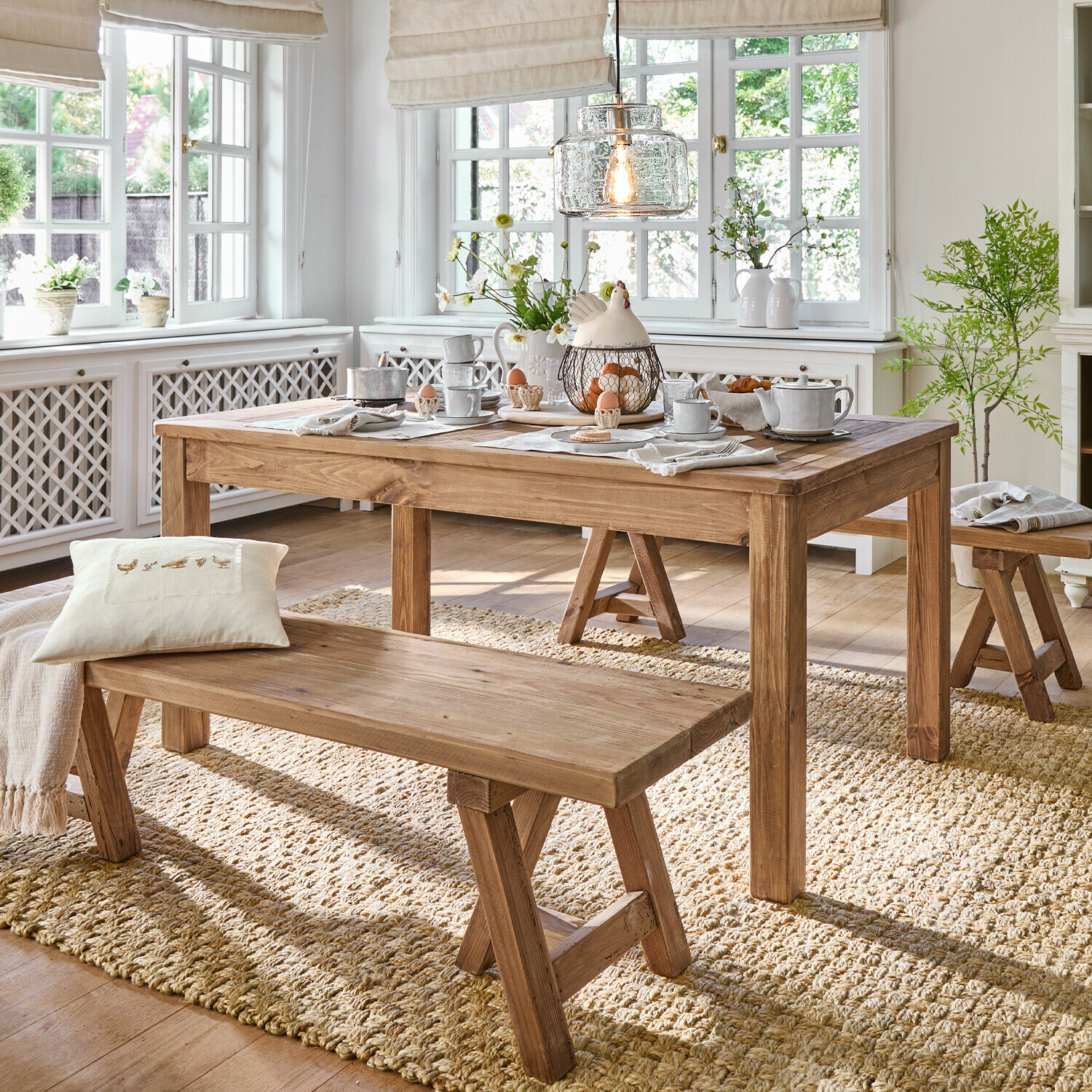 Tafel Amherst Eetkamer met houten tafel en banken op natuurlijke vloerkleed, lichte inrichting met decoraties en licht