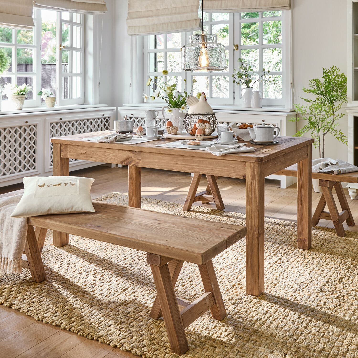 Tafel Amherst Eetkamer met houten tafel en banken op natuurlijke vloerkleed, lichte inrichting met decoraties en licht