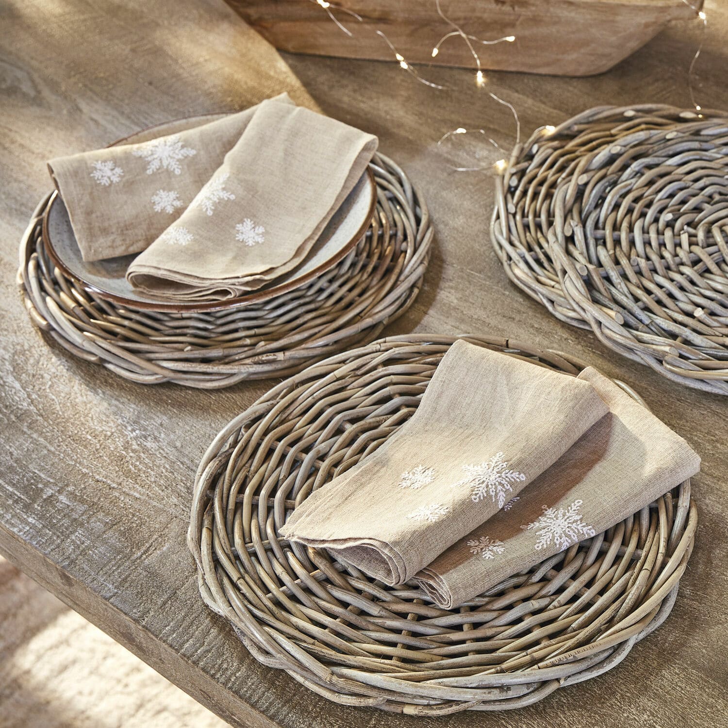 Lot de 4 serviettes Ruspi Serviettes en lin beige avec broderie flocons sur sets en osier sur table en bois rustique