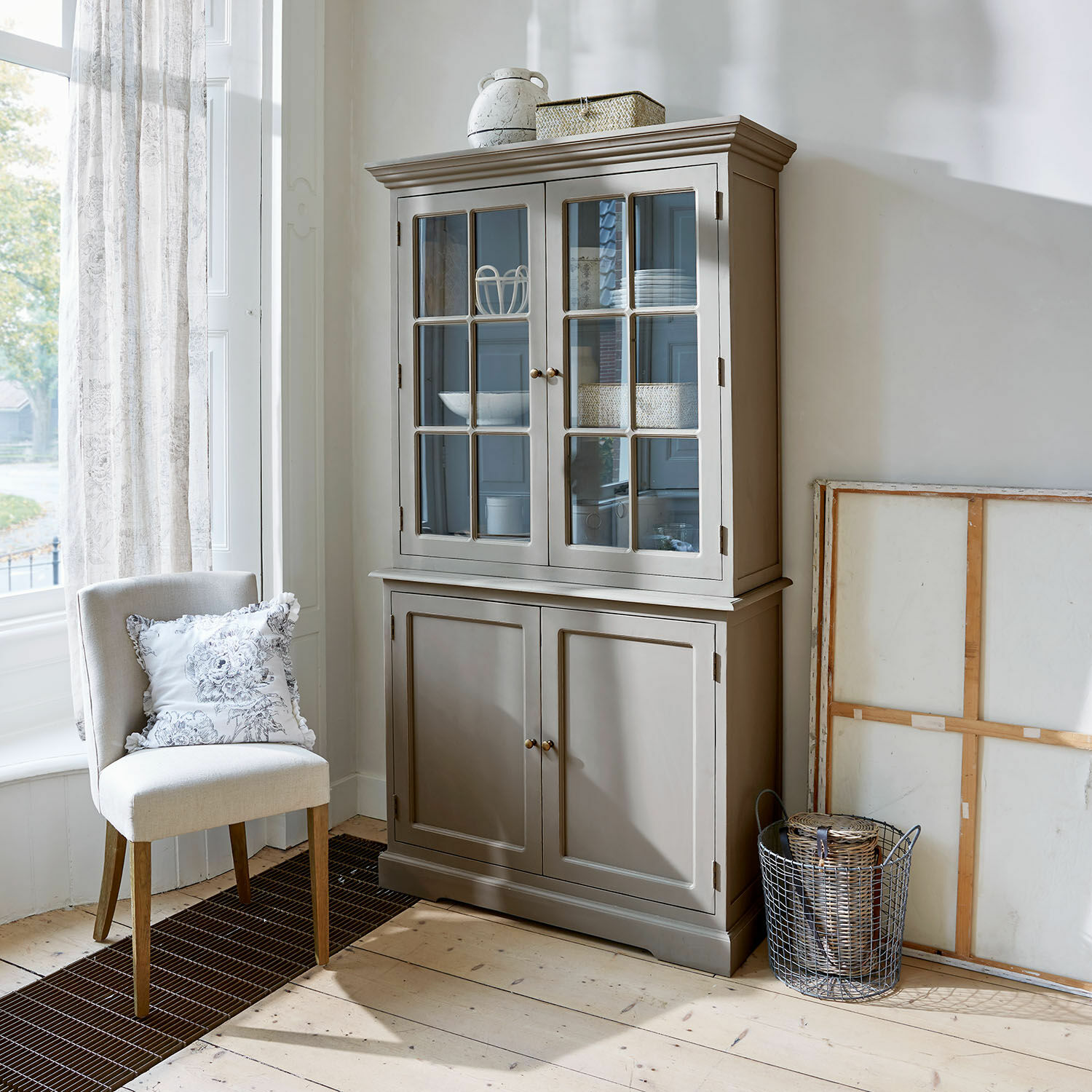 Vaisselier Rosebrook Vitrine en bois grise avec portes vitrées et étagères dans un salon lumineux