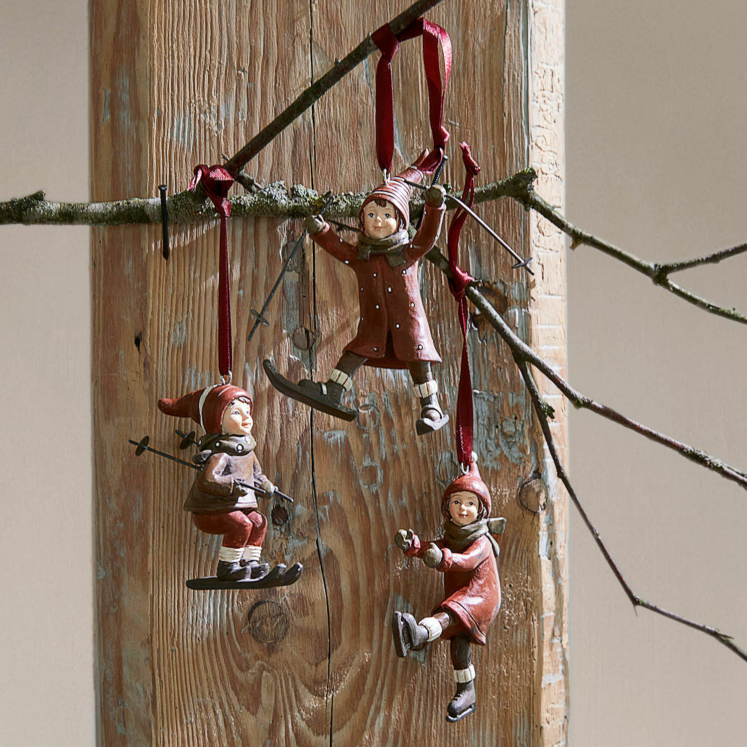 Hanger set van 3 Bibury Drie rode hangers met kinderen op ski's en schaatsen aan houten achtergrond, winterdecoratie