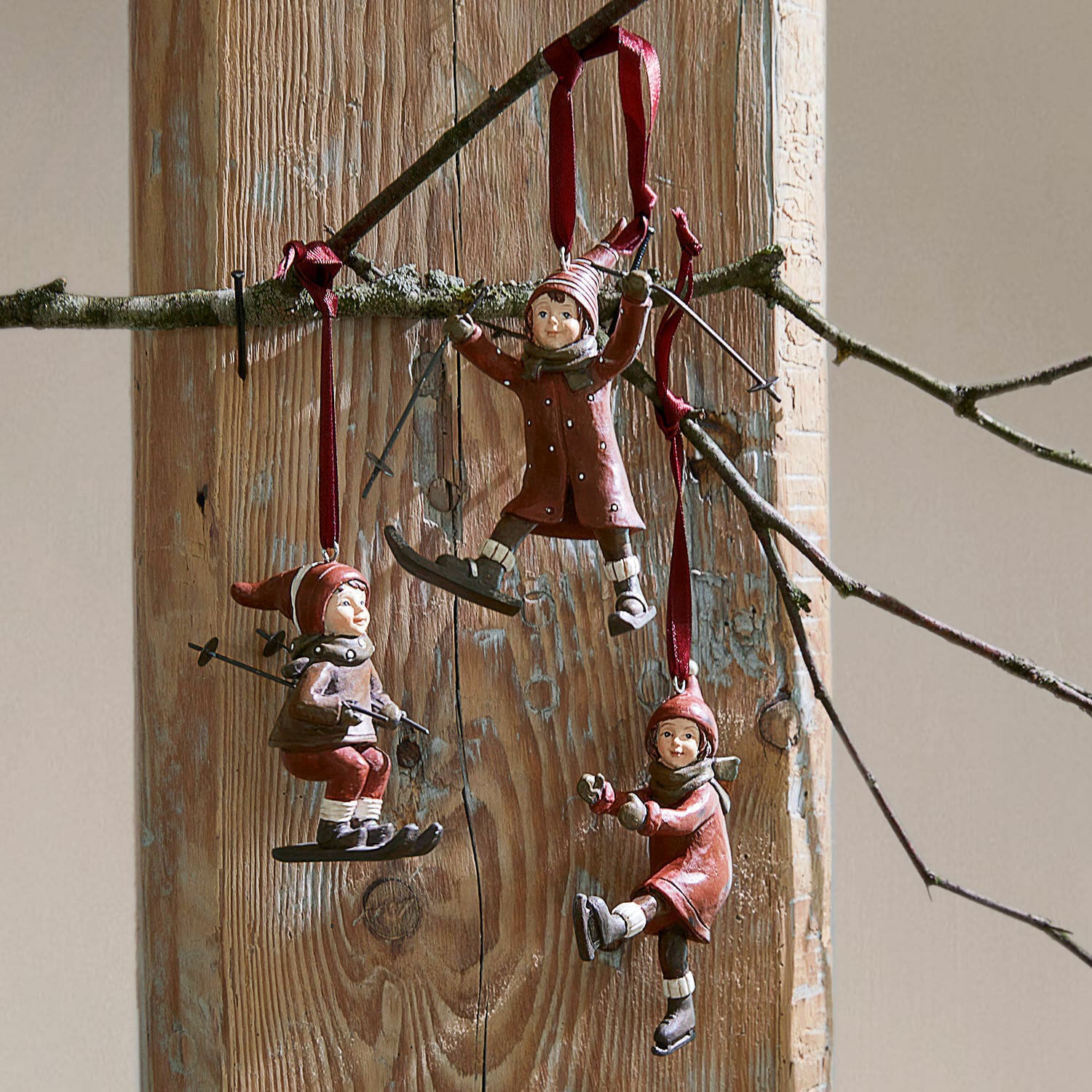 Hanger set van 3 Bibury Drie rode hangers met kinderen op ski's en schaatsen aan houten achtergrond, winterdecoratie