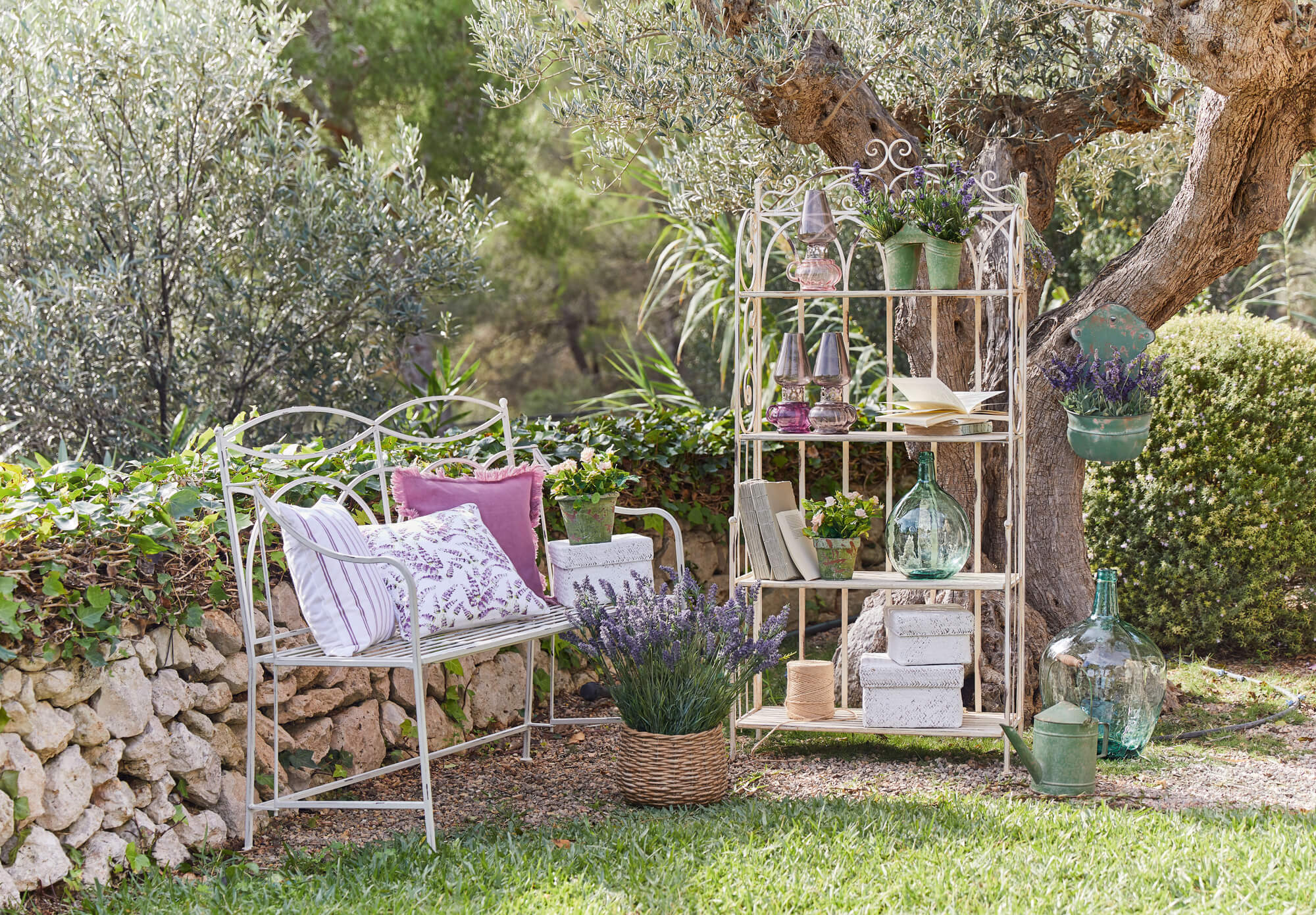 Witte metalen kast en bank in tuin met lavendel en decoraties, rustieke tuinmeubelen