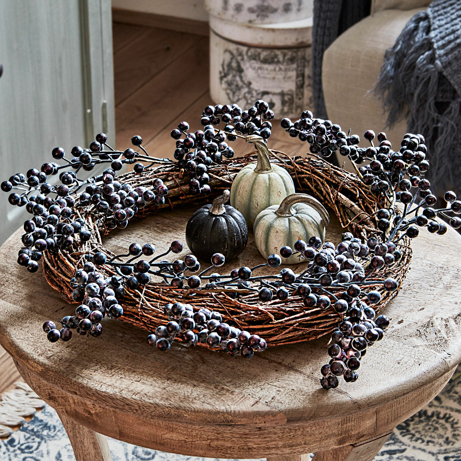 Krans Isabeau Decoratieve krans van takken met zwarte bessen en kleine pompoenen op houten tafel