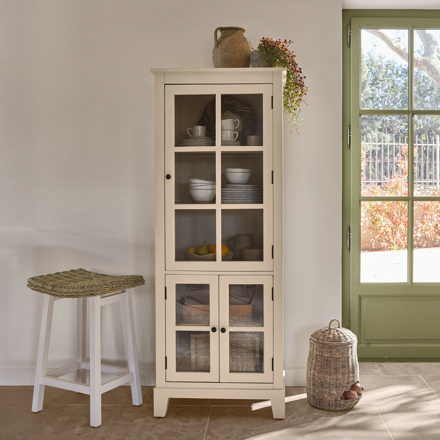 Vitrine Domérise Vitrine en bois blanc avec portes vitrées et décorations en céramique dans un intérieur lumineux