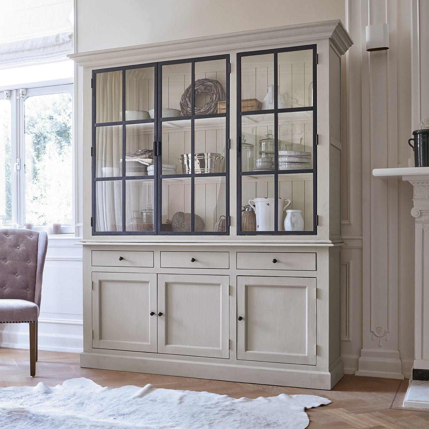 Buffet Thilot Grande vitrine en bois beige avec portes vitrées et tiroirs pour rangement dans un salon lumineux