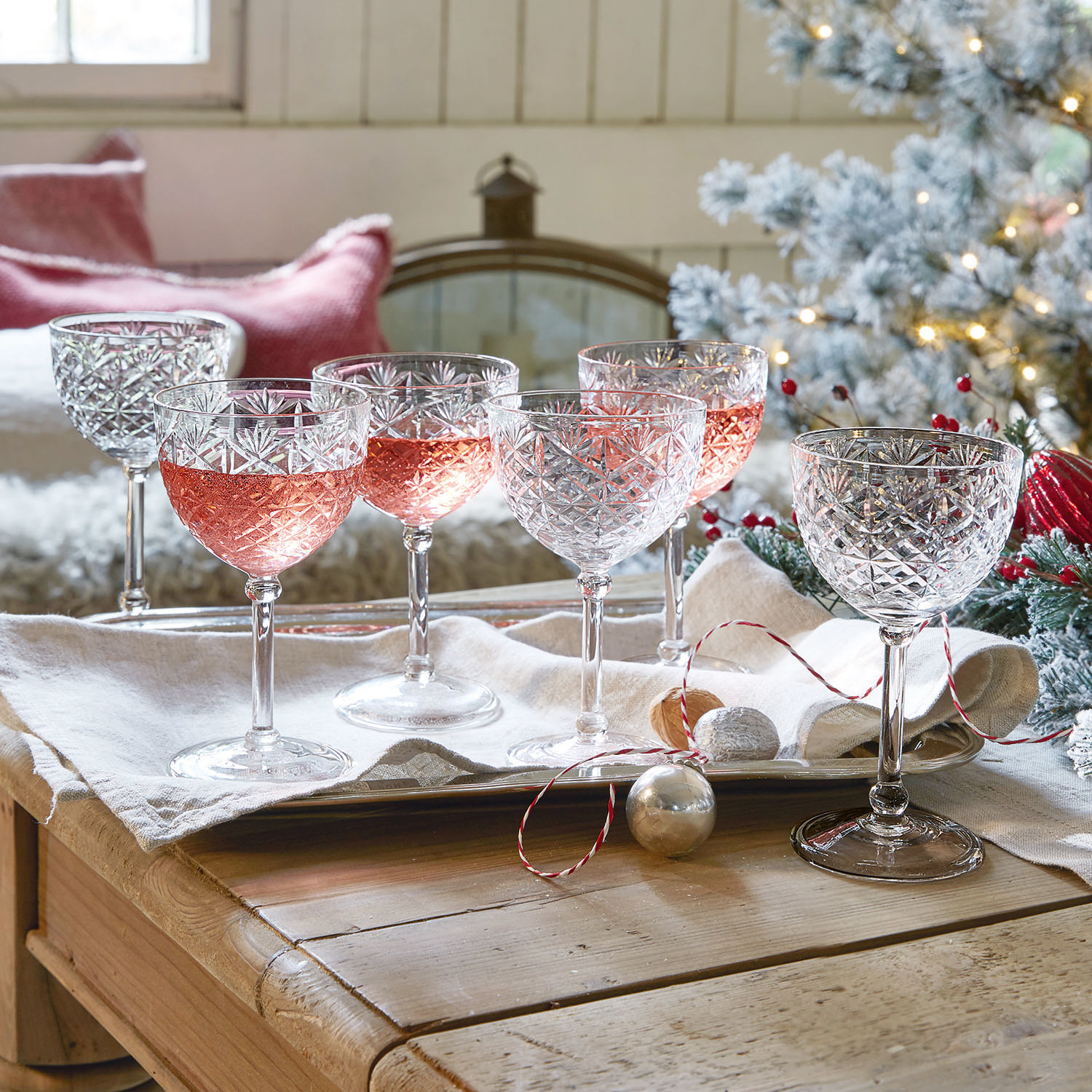 Champagneglas set van 6 Olite Set van zes kristallen wijnglazen met geslepen patroon, deels gevuld met roséwijn, feestelijke setting