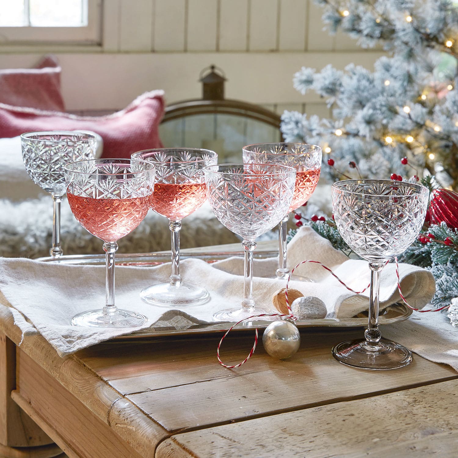 Lot de 6 coupes Olite Ensemble de six verres à vin en cristal avec motif gravé, certains remplis de vin rosé, décor festif
