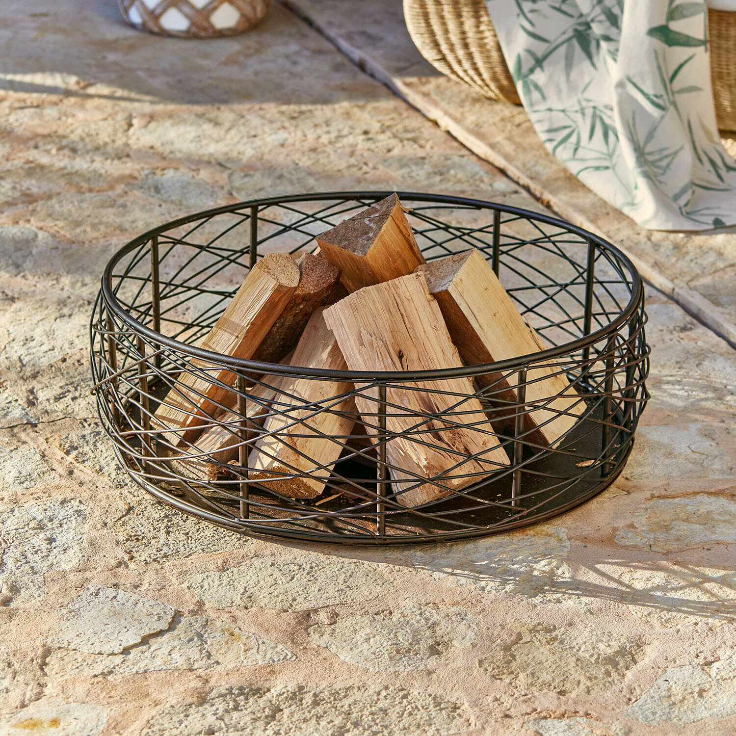 Zwarte metalen mand met natuurlijk haardhout op stenen vloer voor houtopslag bij open haard