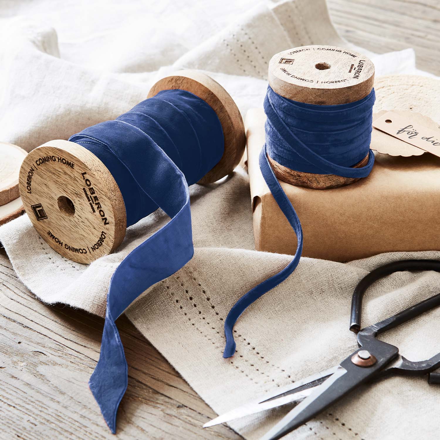 Blauwe fluwelen lint op houten spoelen met schaar op linnen stof voor decoratie en handwerk