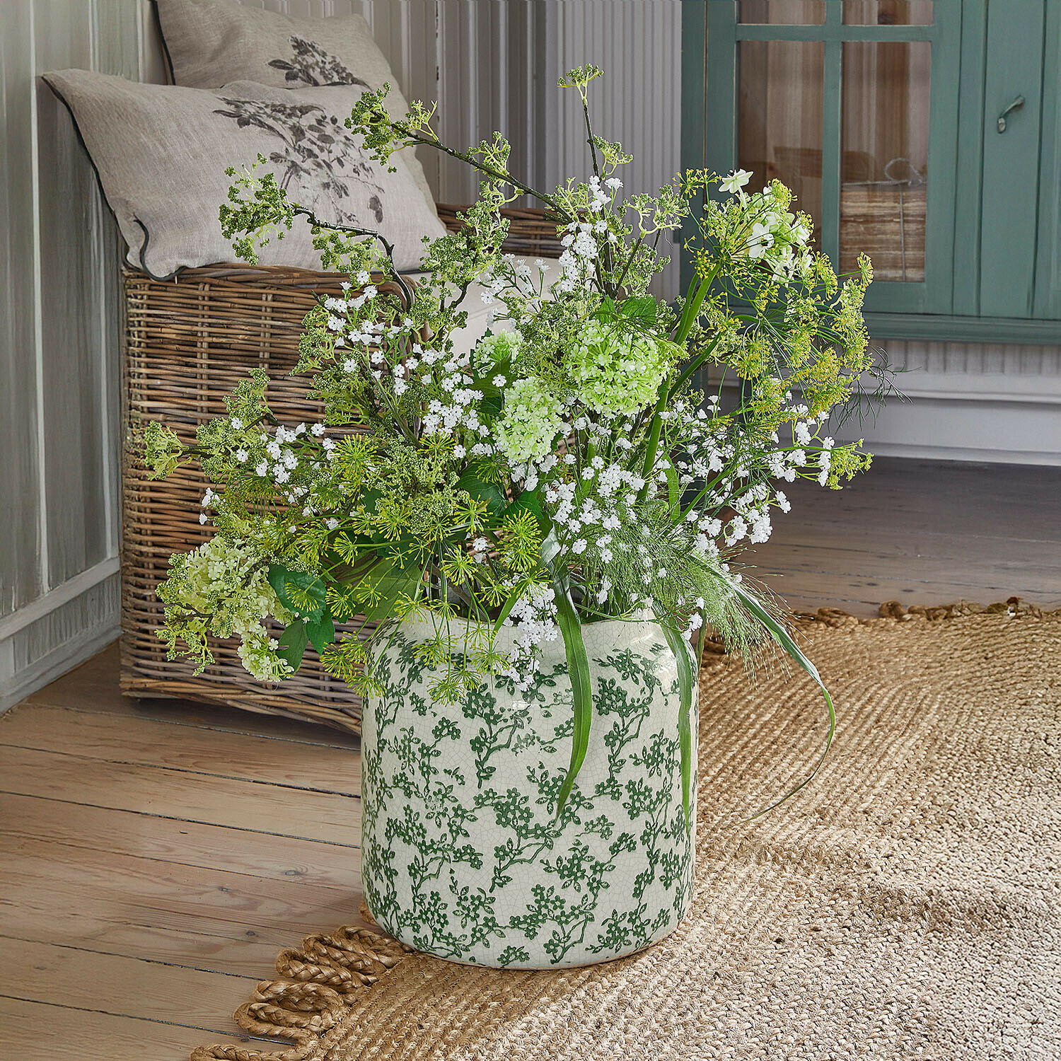 Vaas Vaudrisse Witte keramische vaas met groen patroon, witte bloemen en groene takken op houten vloer