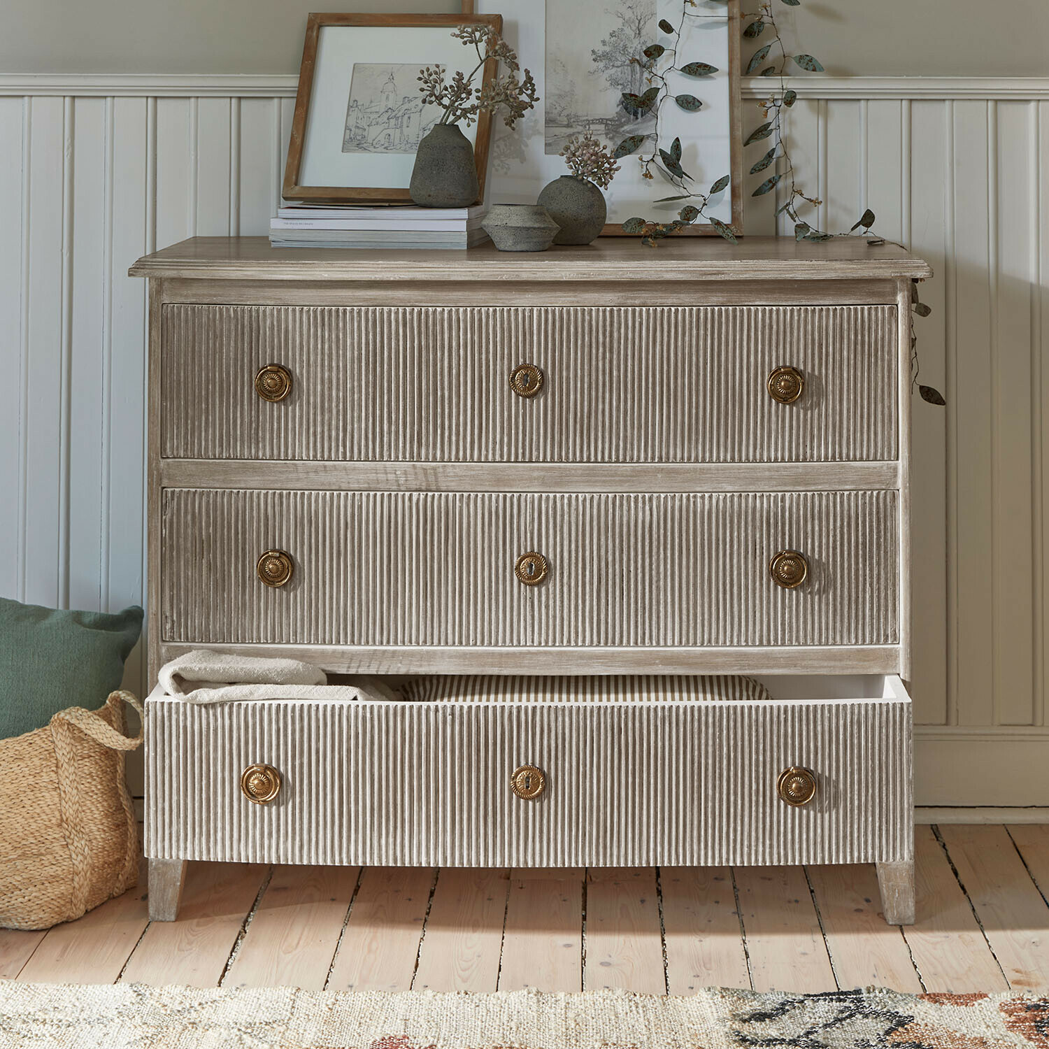 Commode Boissiére Commode en bois nervuré beige avec poignées en laiton et décorations sur le dessus