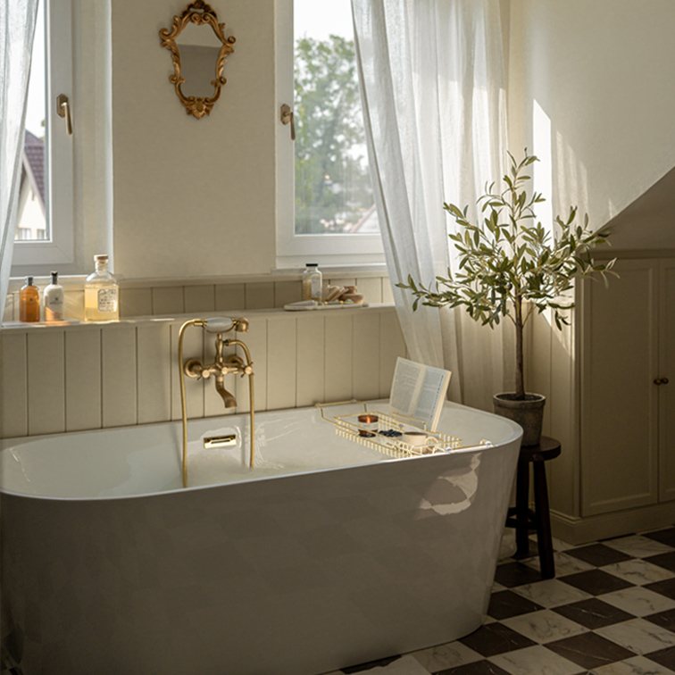 Witte vrijstaande badkuip met messing kraan en decoratieve spiegel in lichte badkamer met plant