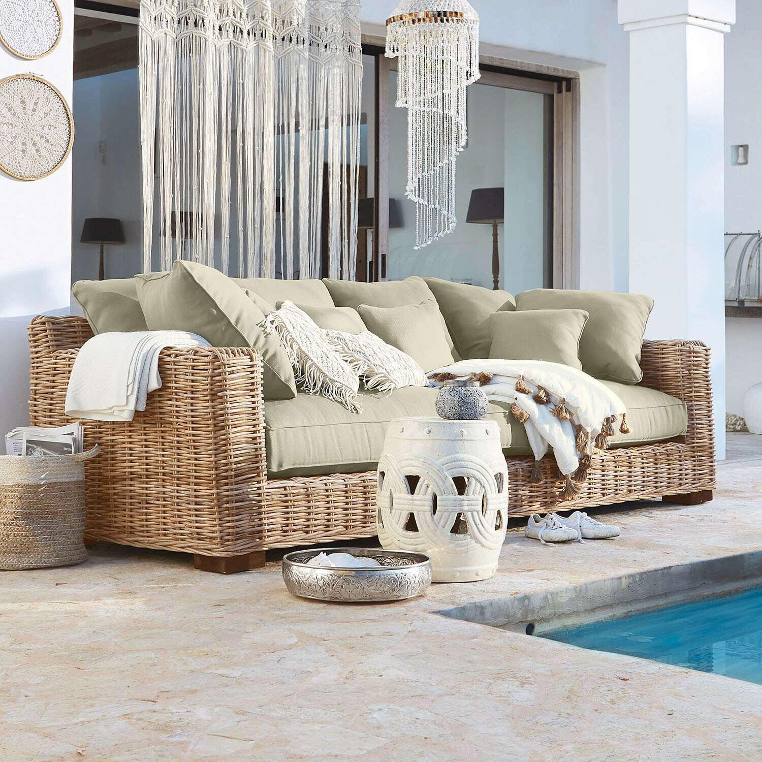Bank Rimini Rotan bank met beige kussens en boho decoraties bij het zwembad