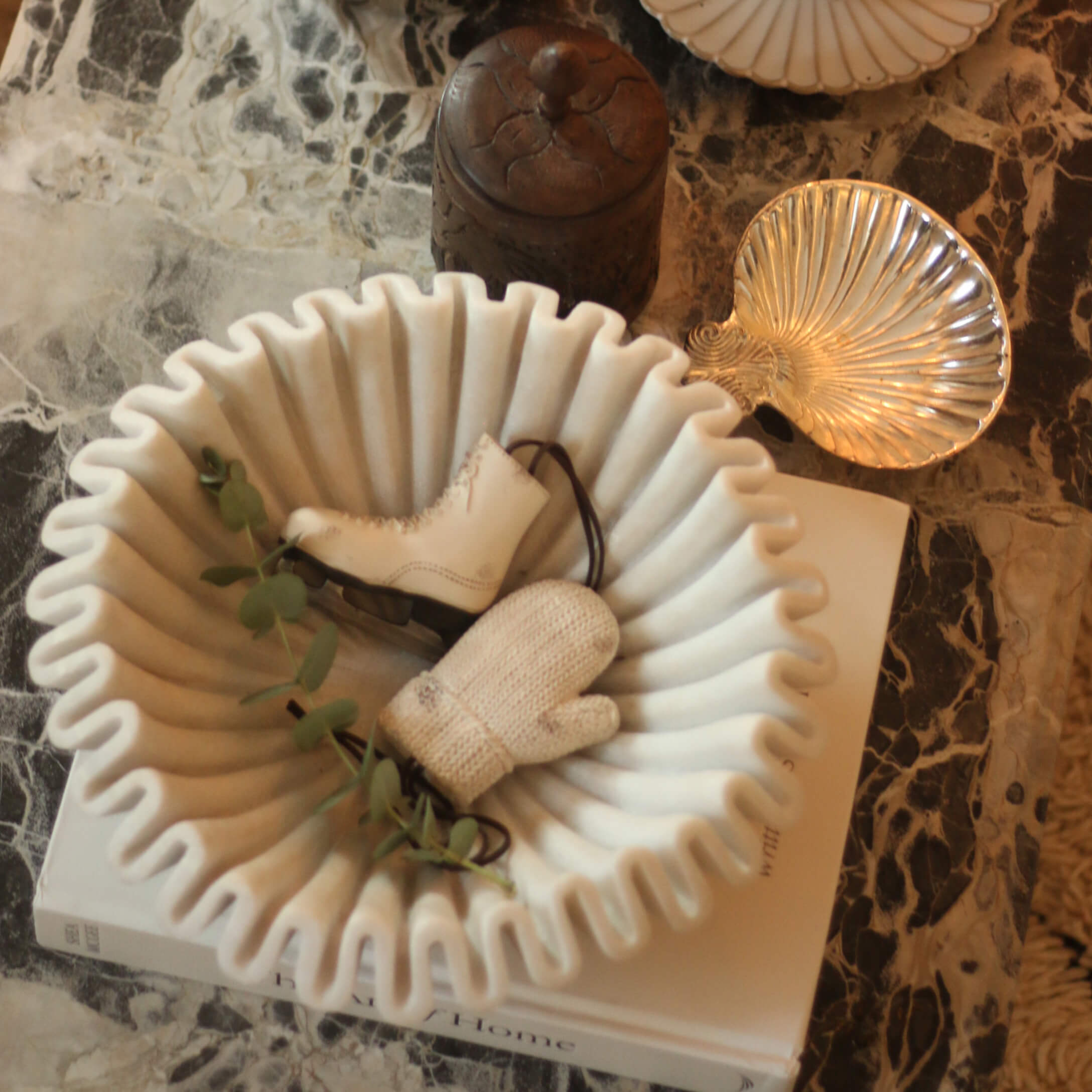 Bol en céramique blanche à bords ondulés avec décorations patin et moufle sur table en marbre