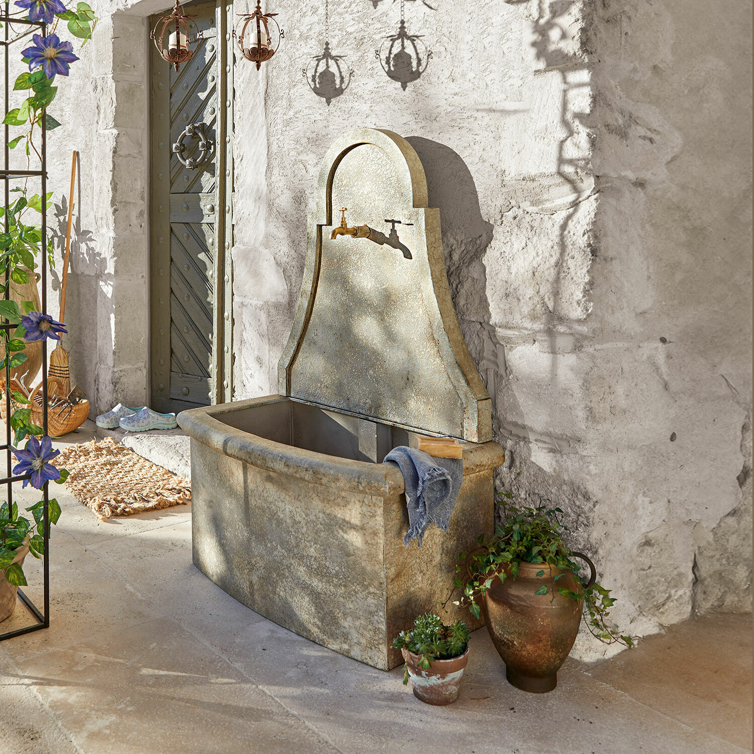 Fontaine Albury Fontaine de jardin en pierre grise avec robinet en laiton et plantes décoratives à côté