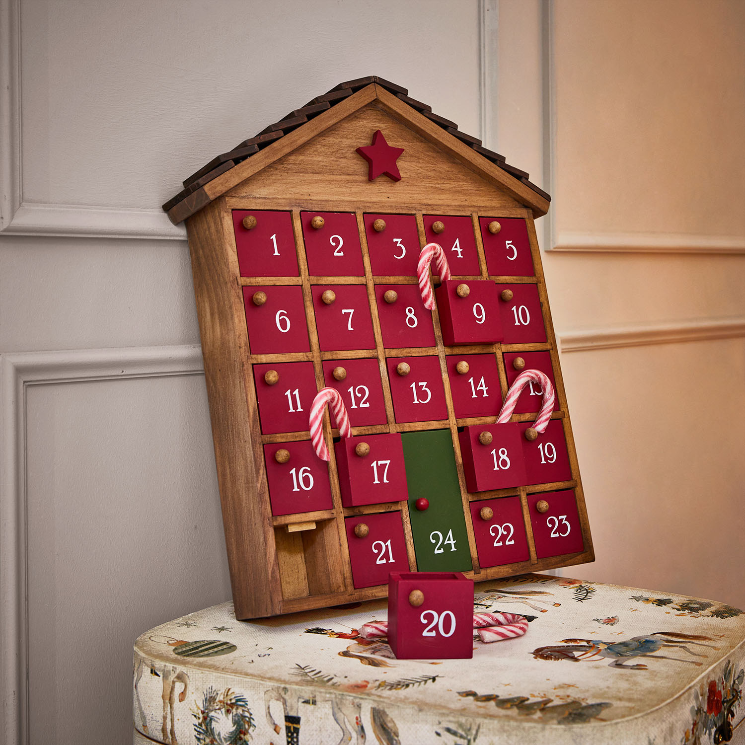 Calendrier de l'Avent en bois en forme de maison avec portes rouges et numéro 24 vert, décoré de sucres d'orge