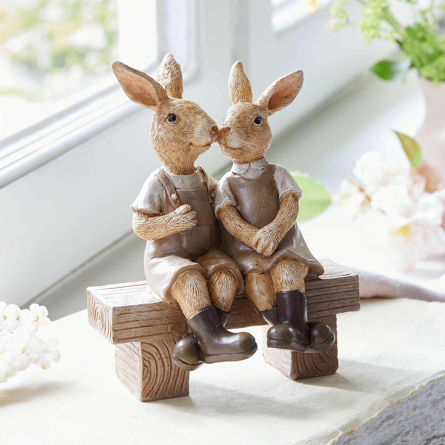 Haasjes Faylin Beeldjes van twee bruine konijnen van hars met kleding zittend op een decoratieve houten bank