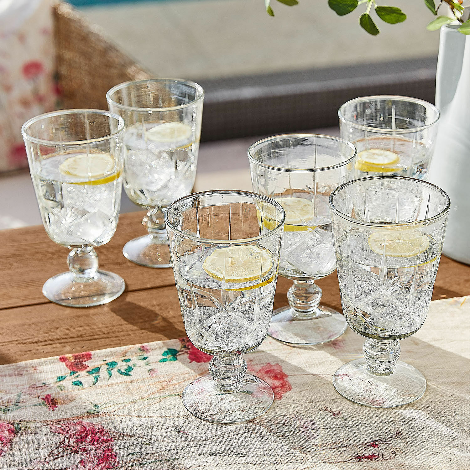 Glas set van 6 Mirathor Set van zes transparante glazen met voet, water, ijsblokjes en citroenschijf op houten tafel