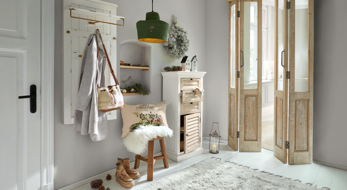 Gezellige ruimte met houten kast, groene lamp en kerstdecoratie in lichte kleuren