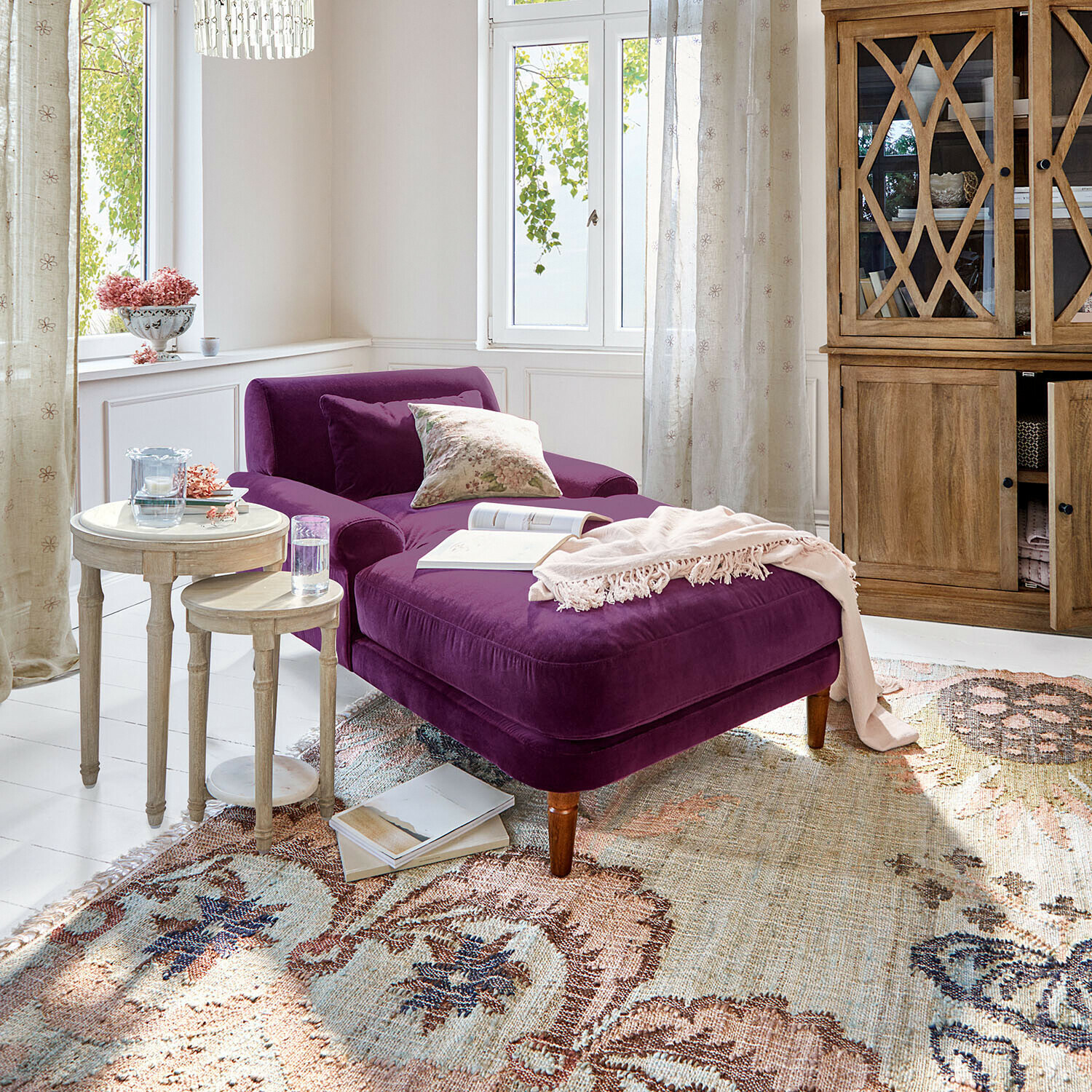 Chaise longue Jouvrelle Paarse fluwelen chaise longue in lichte woonkamer met houten kast en twee ronde bijzettafels