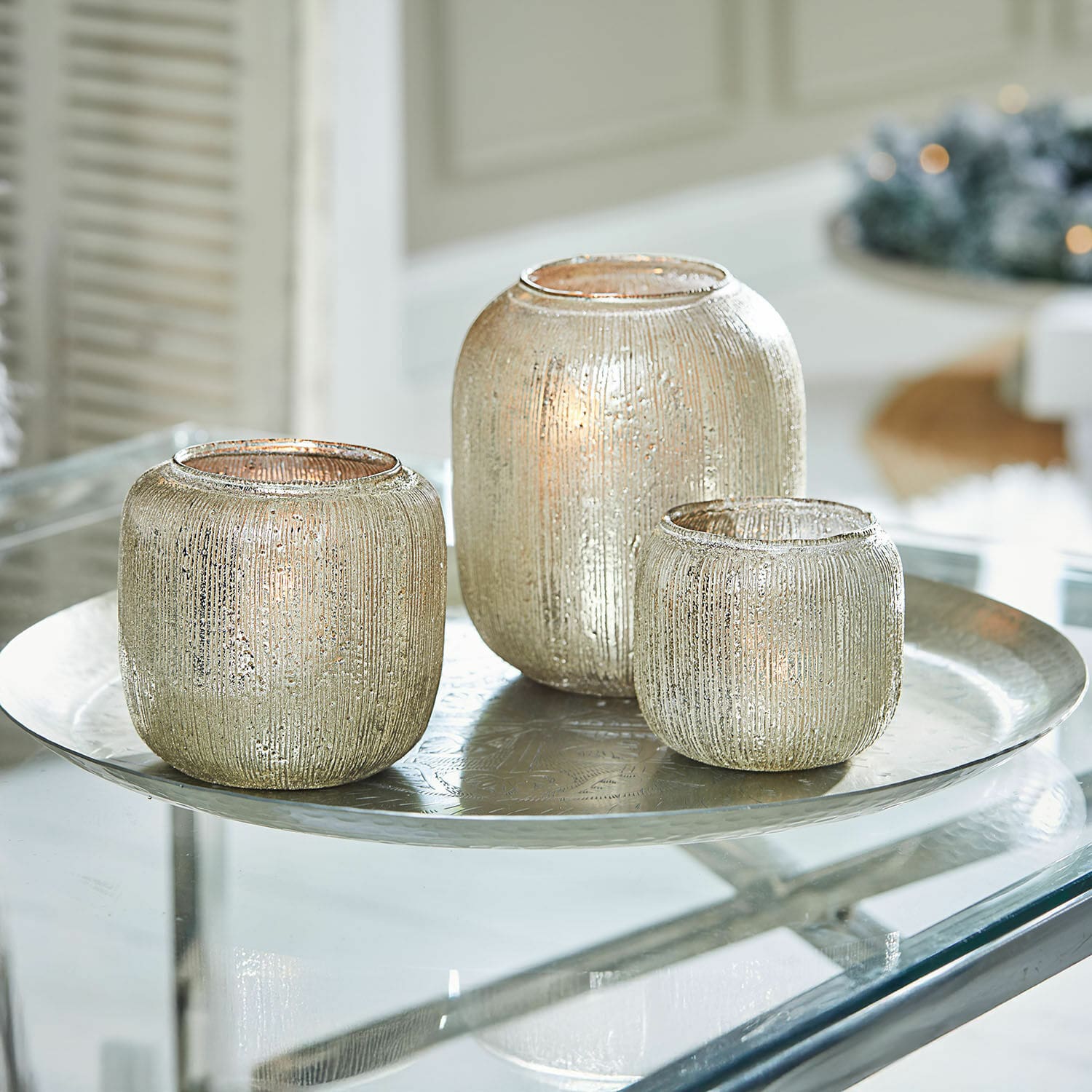 Lot de 3 photophores Clioneth Ensemble de trois photophores en verre argenté avec surface texturée sur un plateau métallique