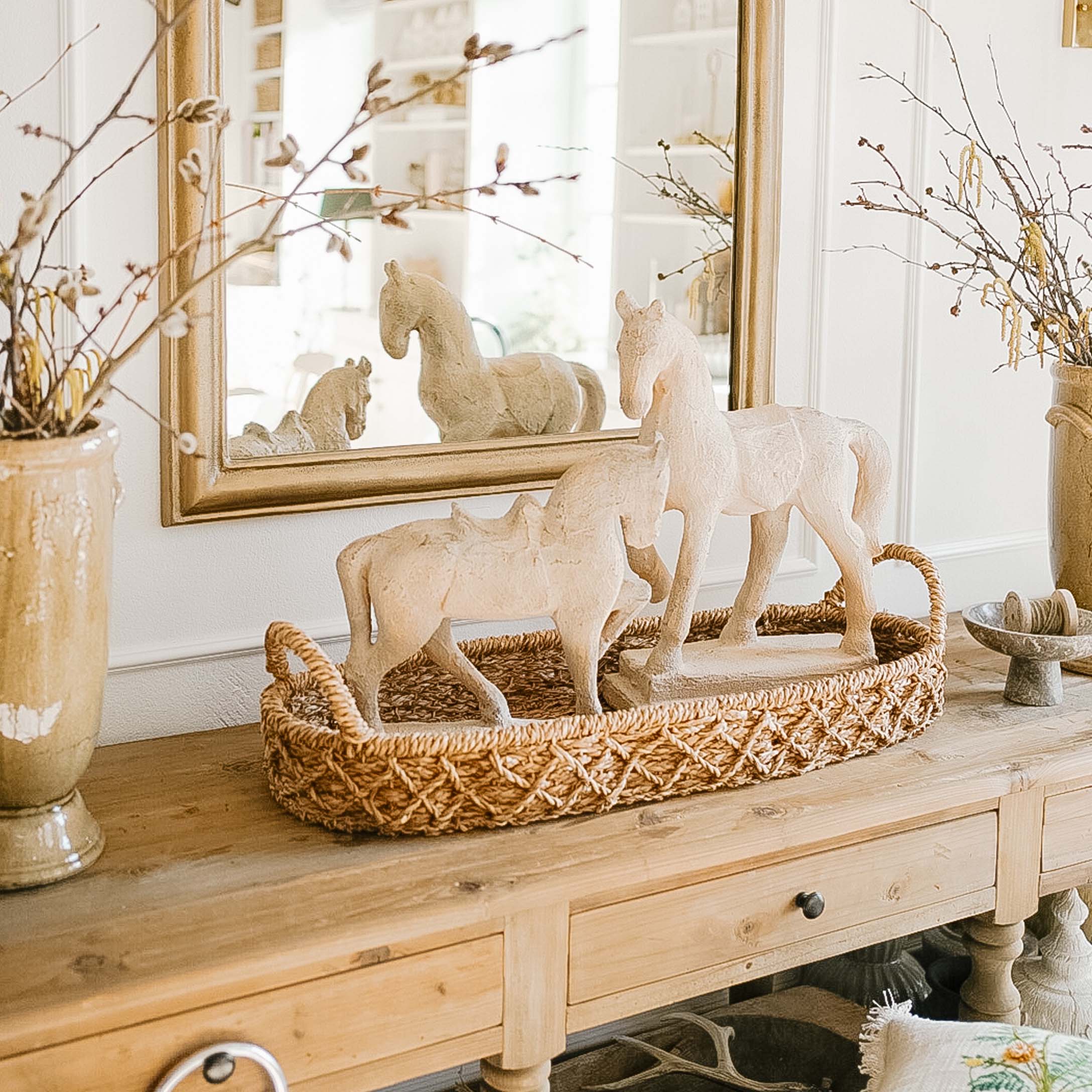 Figurines blanches de chevaux en matériau sur un plateau tressé marron sur une table en bois