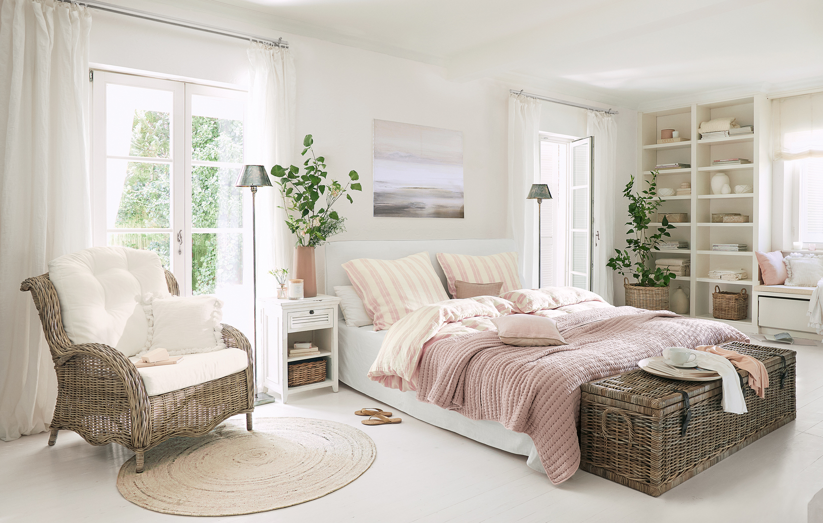 Chambre chaleureuse style campagne avec fauteuil en osier et couverture rose sur le lit
