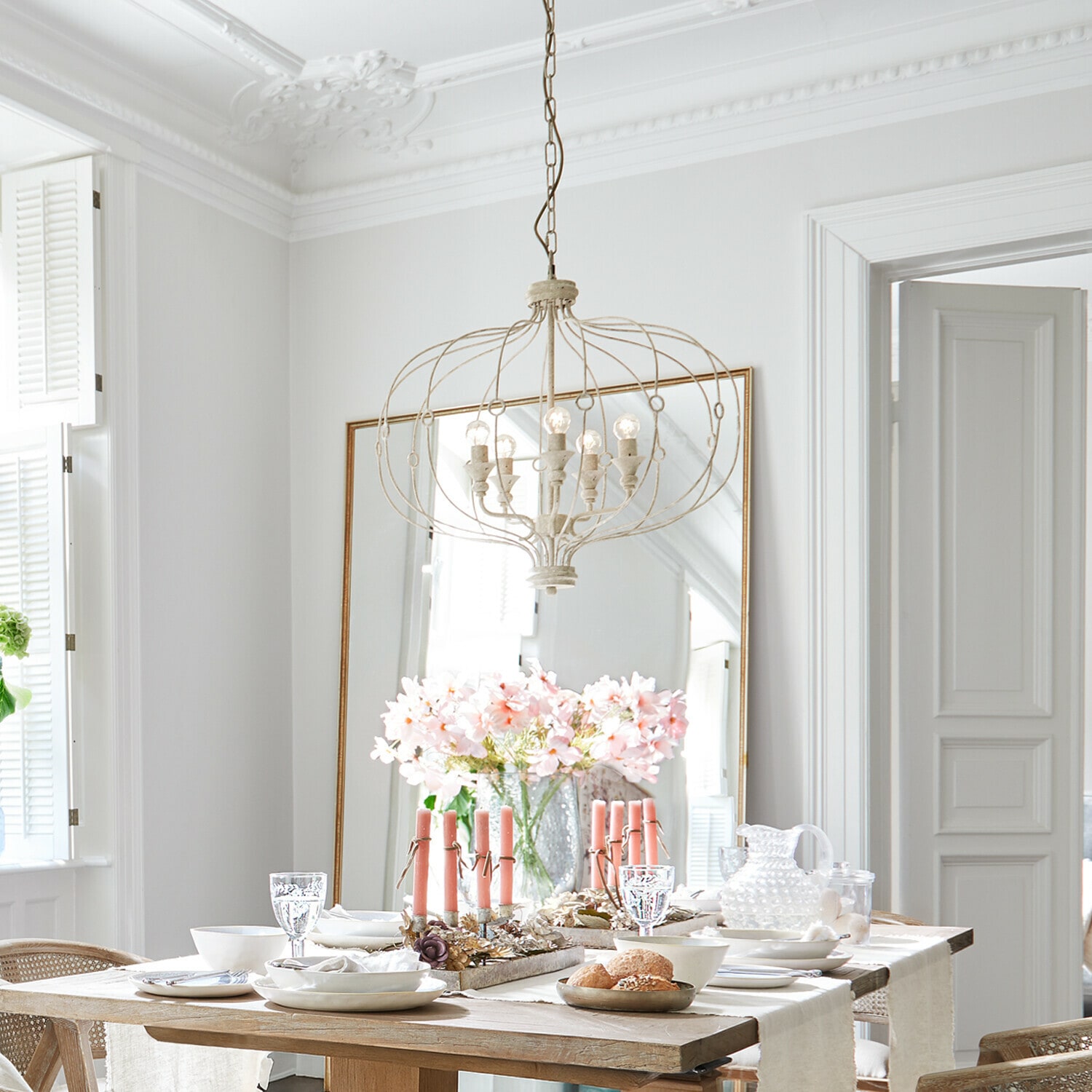 Kroonluchter Aragonese Lichte eetkamer met houten tafel, roze kaarsen en vintage metalen hanglamp aan het plafond