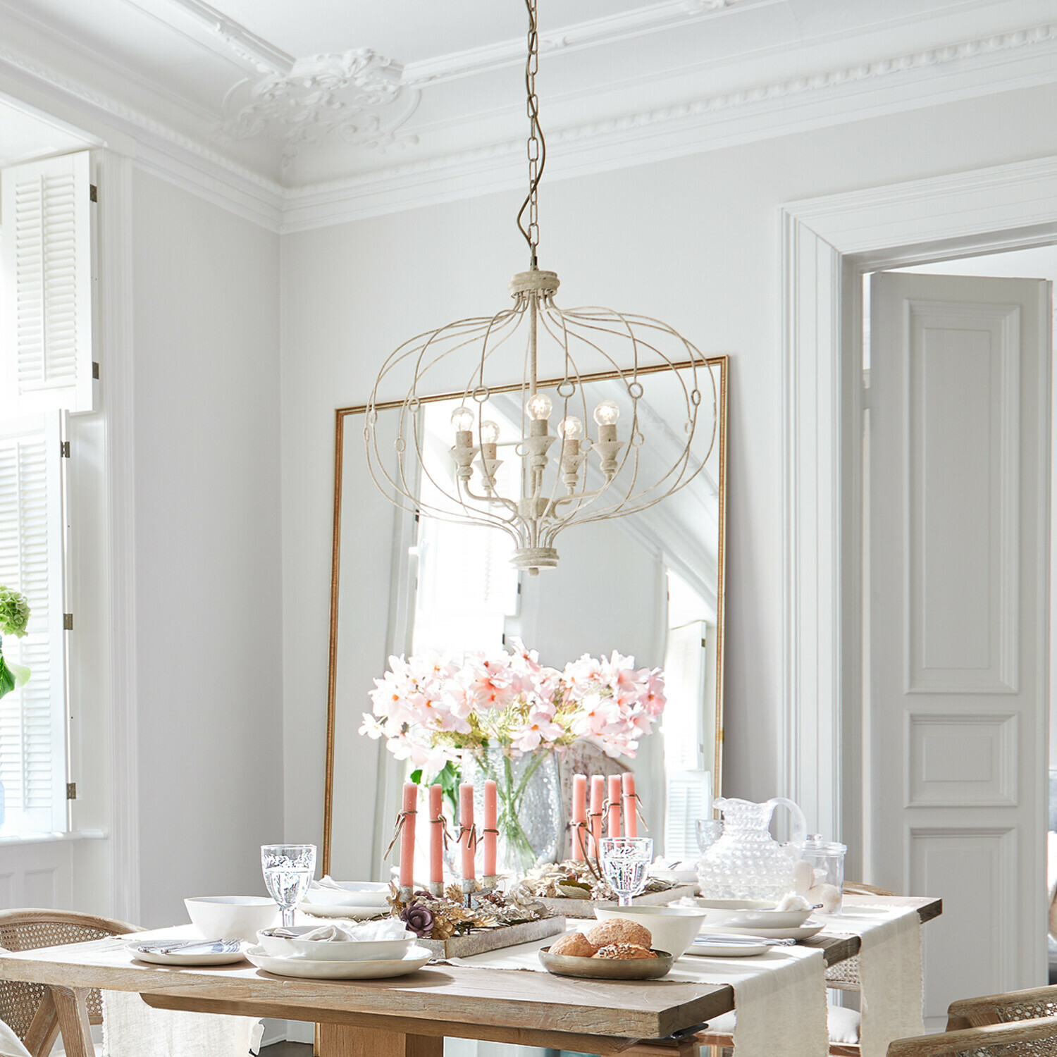 Kroonluchter Aragonese Lichte eetkamer met houten tafel, roze kaarsen en vintage metalen hanglamp aan het plafond