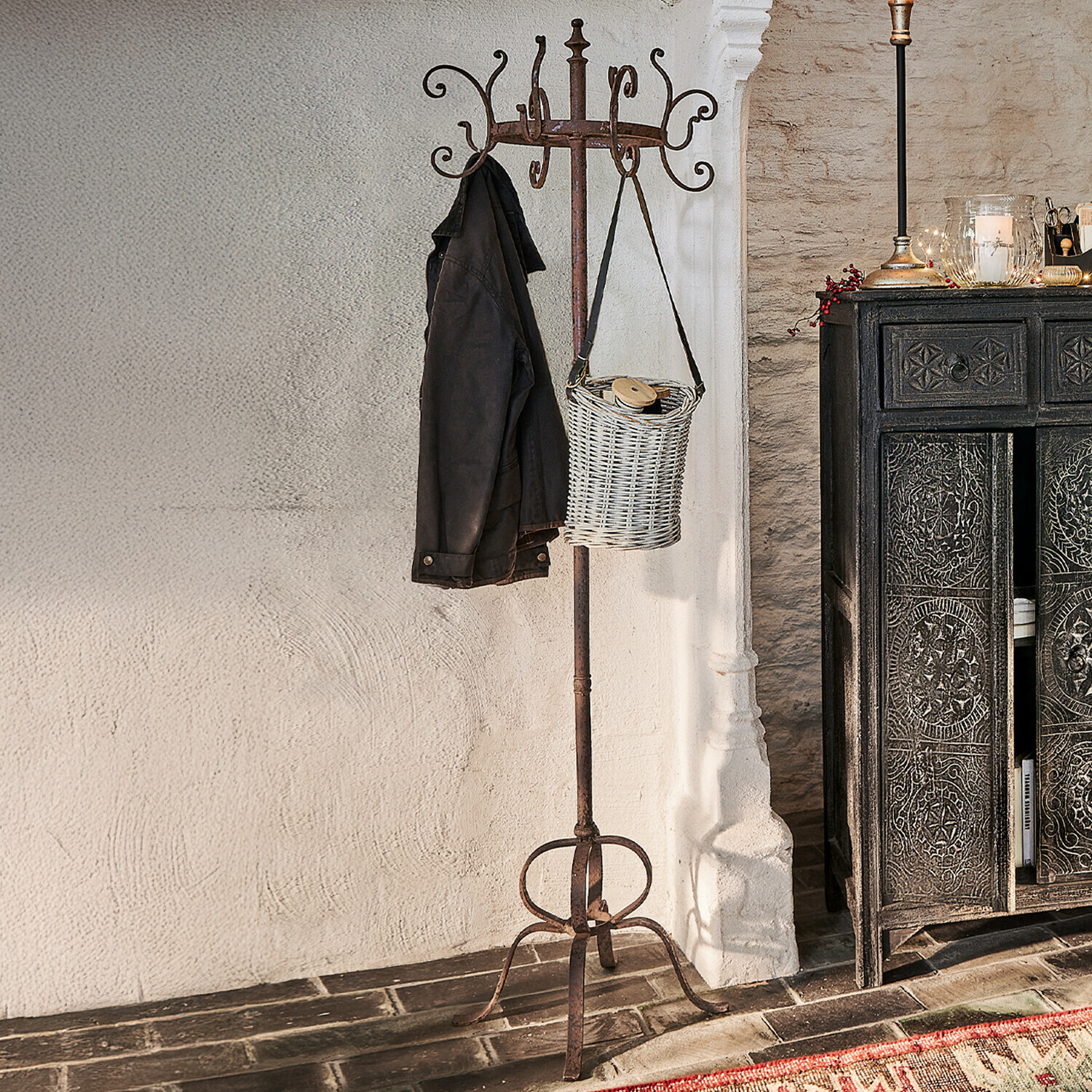 Portemanteau Arlington Porte-manteau en métal rouillé à côté d'un meuble noir sculpté en bois dans un salon rustique
